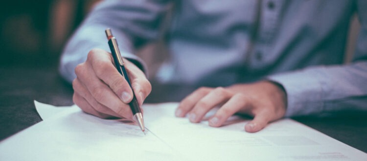 Businessman Writing on Documents with Pen