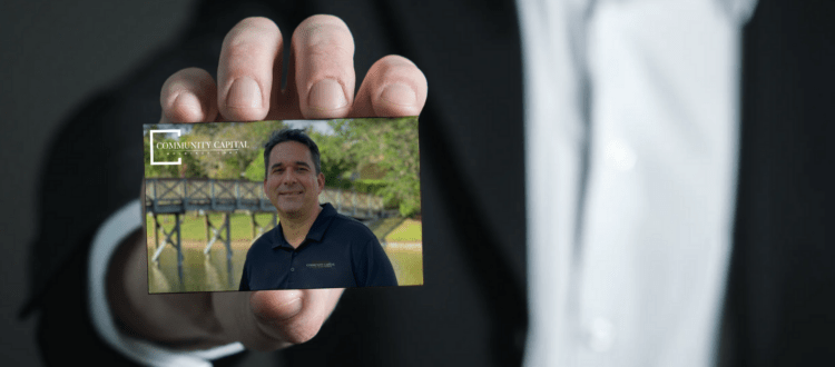 Businessman Holding Eric Servaites Community Capital Business Card