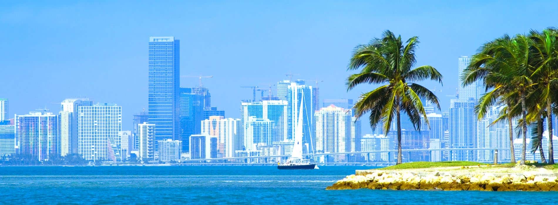 View of Miami Skyline across the Ocean with skyscrapers and a boat in the water