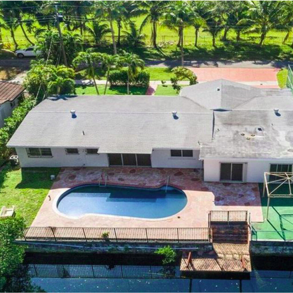Aerial view of Residential Property with Large Backyard and Pool in Southern Florida across from a field of Palm trees