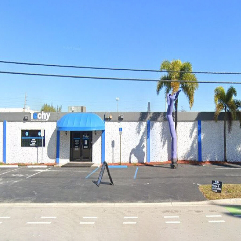 Blue and White Commercial and Manufacturing Warehouse with Large parking lot and palm trees in South Florida